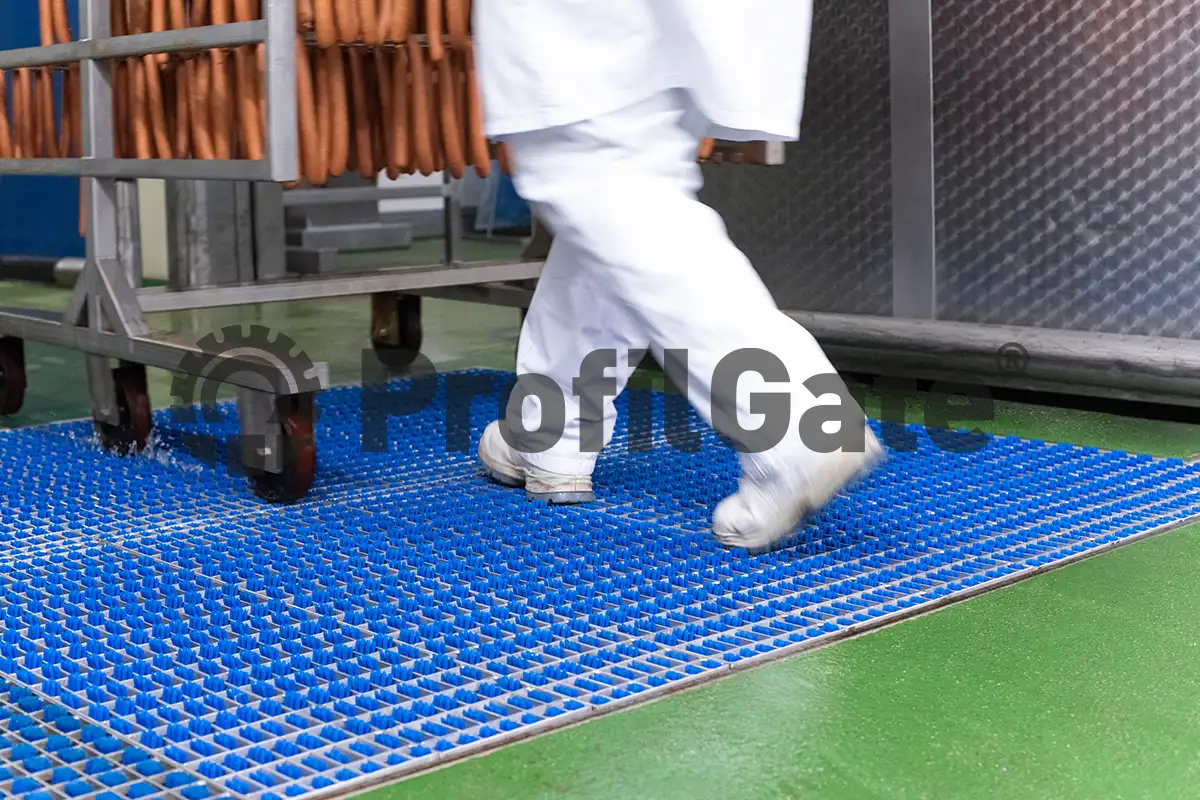 Nahaufnahme eines Regalwagens mit Wurstwaren, fährt über eine Hygieneschleuse mit Desinfektionslösung 