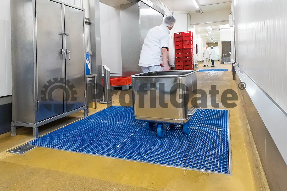 Mitarbeiter in weißem Arbeitskittel zirht Kutterwagen mit Lebensmittelwaren über Hygieneschleuse