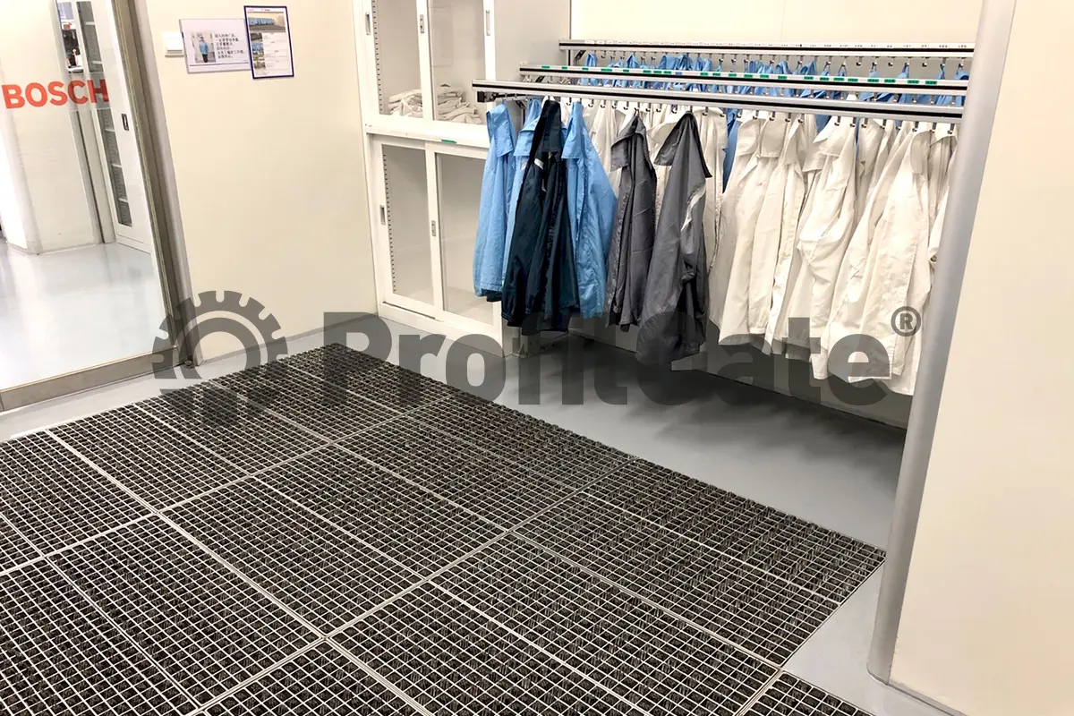 Eine graue SAauberlaufzone in einer Mitarbeiterumkleide vor einer Garderobe mit Arbeitskitteln