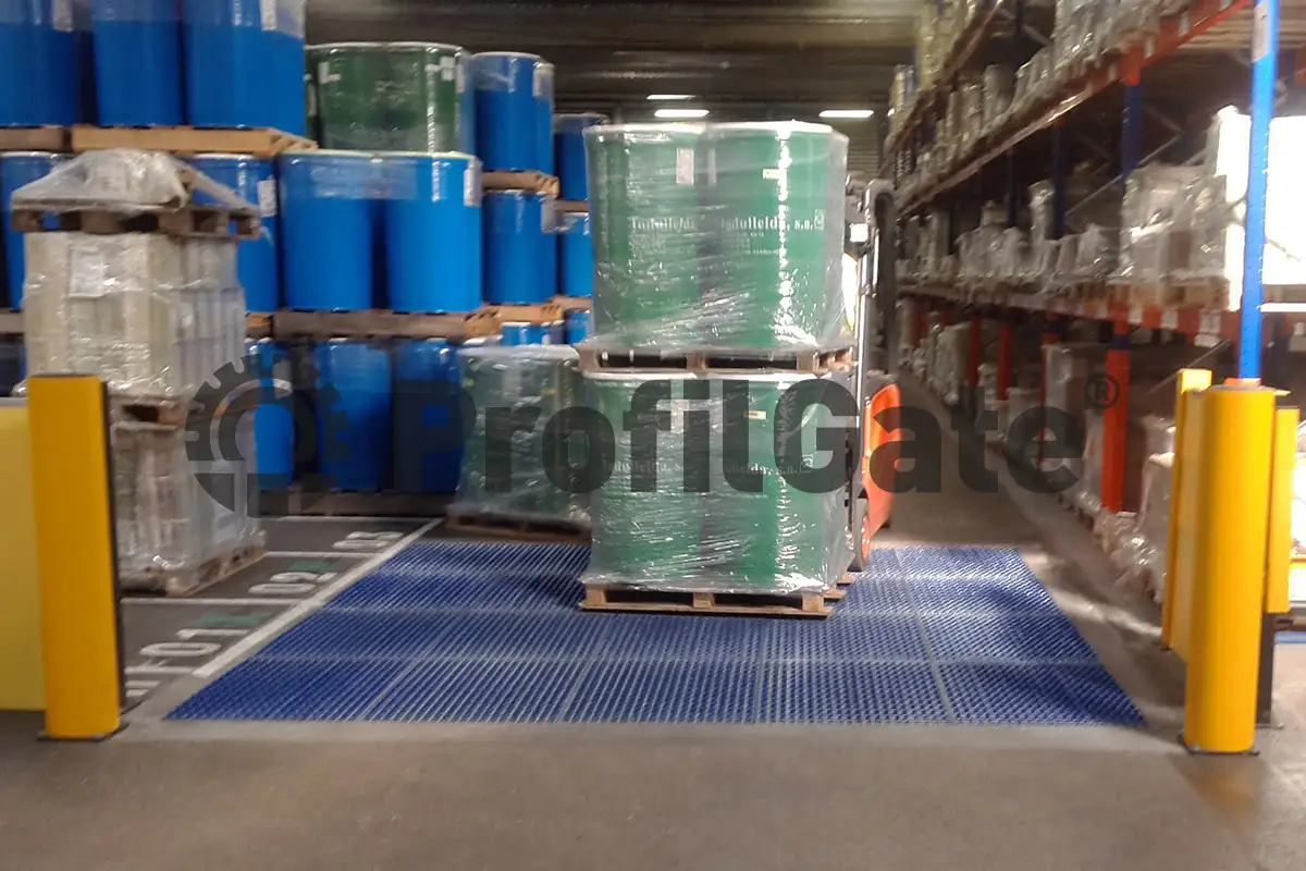 Ein mit Chemikalienfässern beladener Gabelstapler fährt über eine blaue Sauberlaufzone in der Logistik