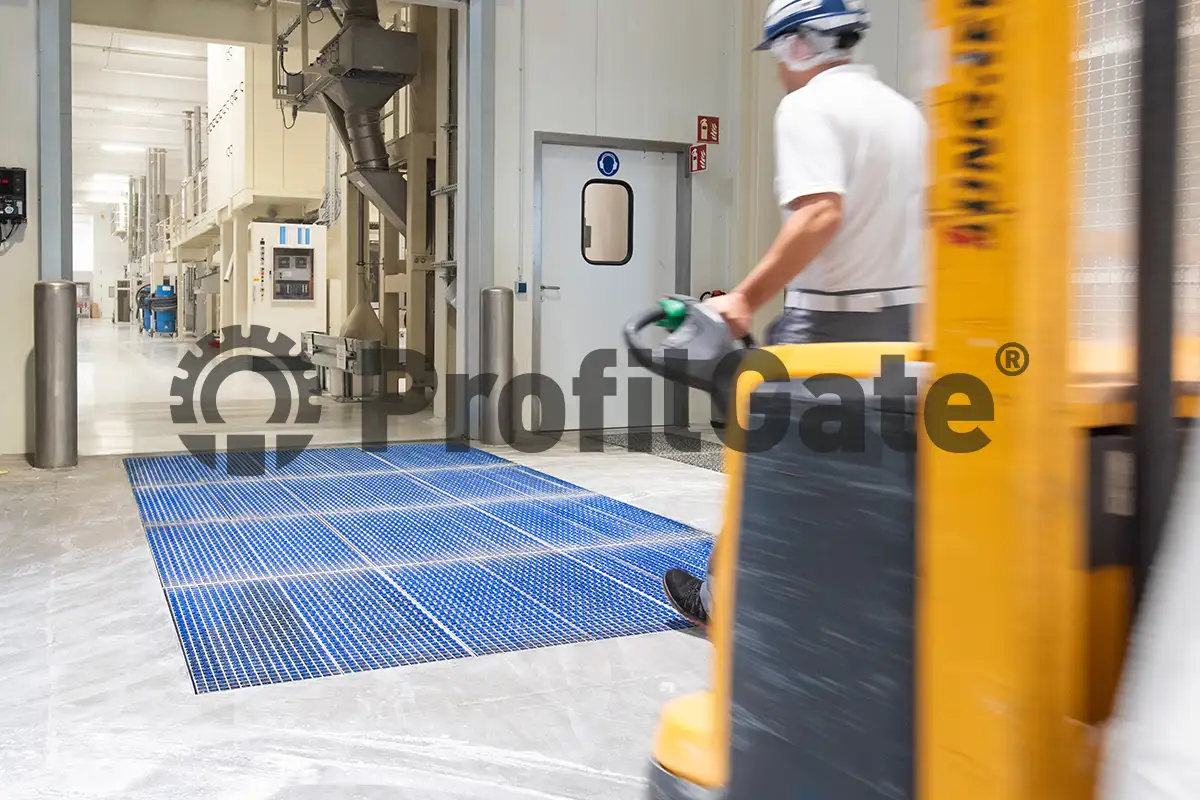Ein Mitarbeiter mit Hubwagen fährt über eine blaue Sauberlaufzone in eine angrenzende Halle