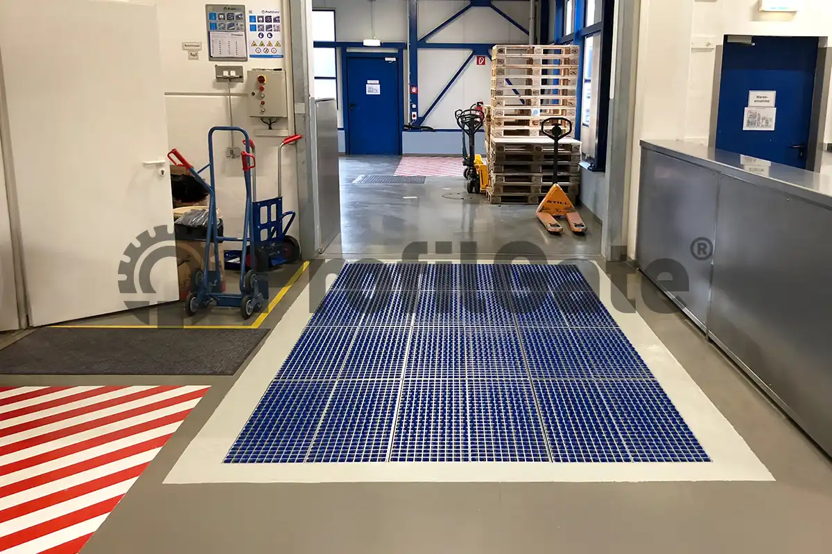 Ein Durchgang zwischen zwei Hallen mit Paletten, Hubwagen und einer blauen Sauberlaufzone