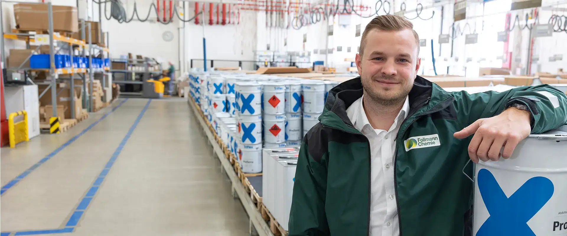 Logistikleiter von Follmann Chemie lehnt an einem Stahlfass und lächelt in die Kamera