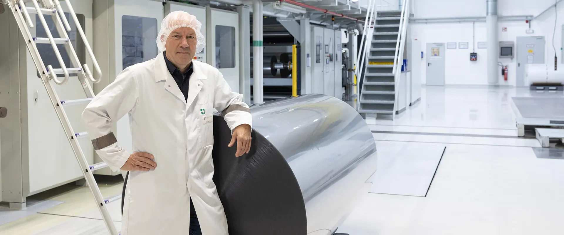 Der Leiter Qualitätsmanagement von Klöckner Pentaplast steht in einer Produktionshalle und lächelt in die Kamera