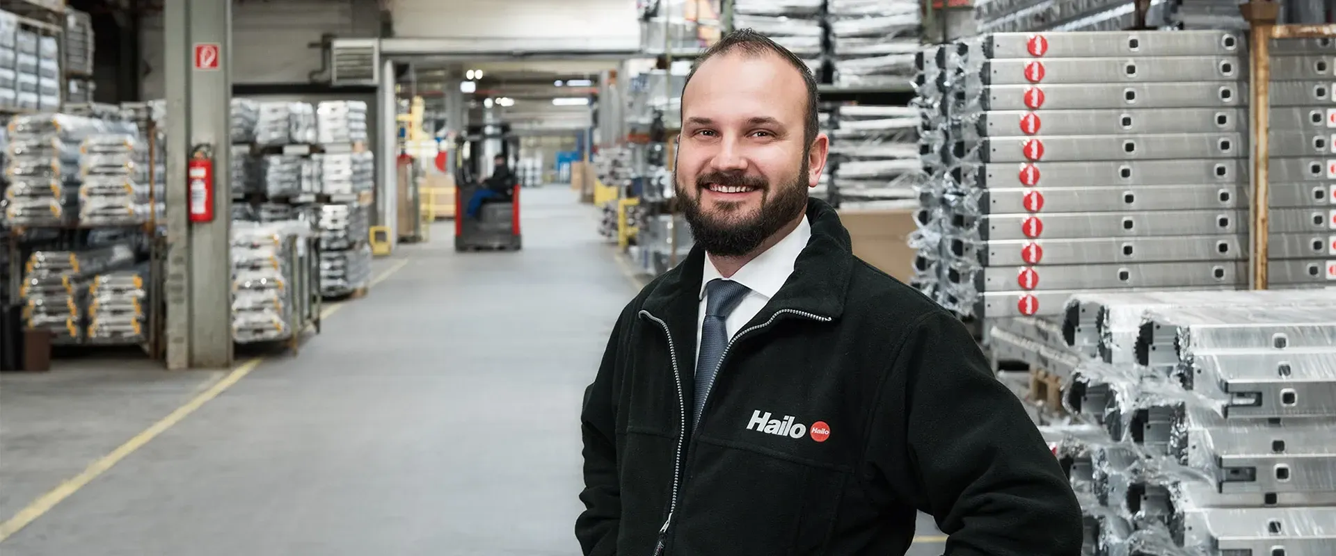Logistik-Manager von Hailo steht in einer großen Lagerhalle und blickt in die Kamera.